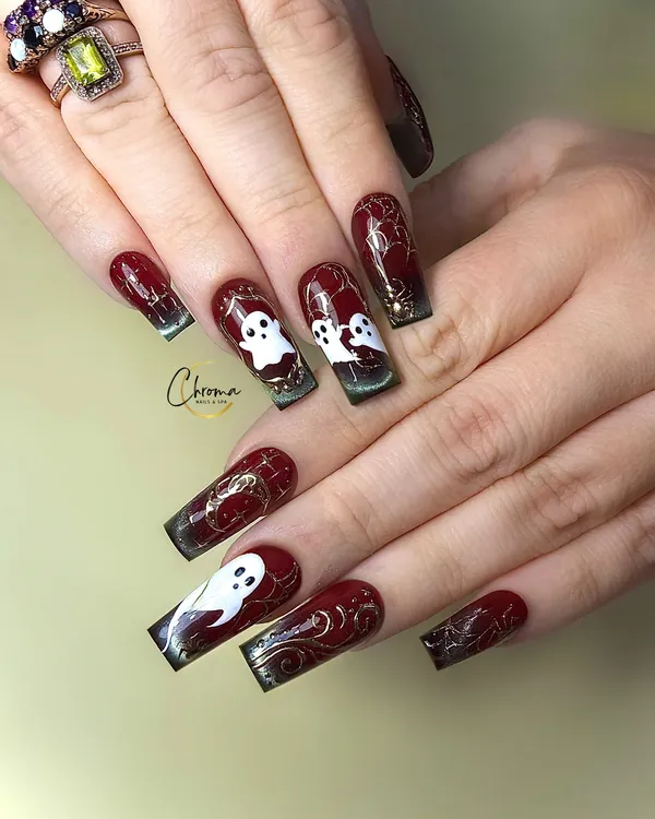 Long deep red nails with white ghosts, gold swirls and dark green tips